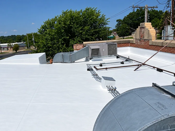 White roof surface around rooftop equipment, pipes and brick parapet (retouched photo)