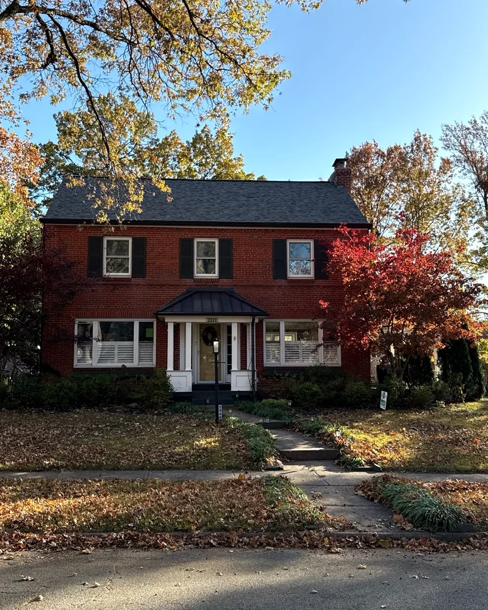 Red brick St. Louis home with dark architectural shingle roof and black shutters.