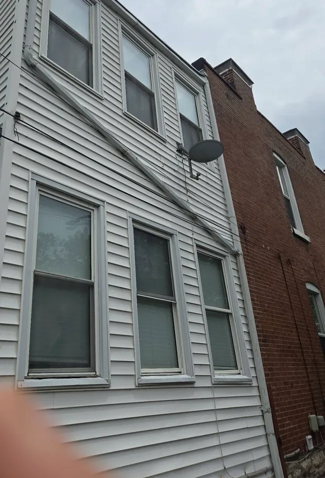 Original white vinyl siding and window trim before the exterior restoration.