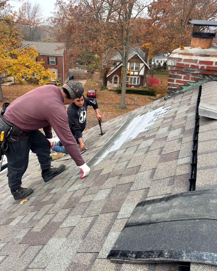 Roofing crew working on a shingled roof with exposed underlayment visible.